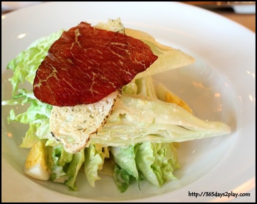 The Olive - Caesar Salad with baby romaine heart, focaccia croute, beef prosciutto, parmesan crisp, quail egg, and white anchovy dressing RM 28