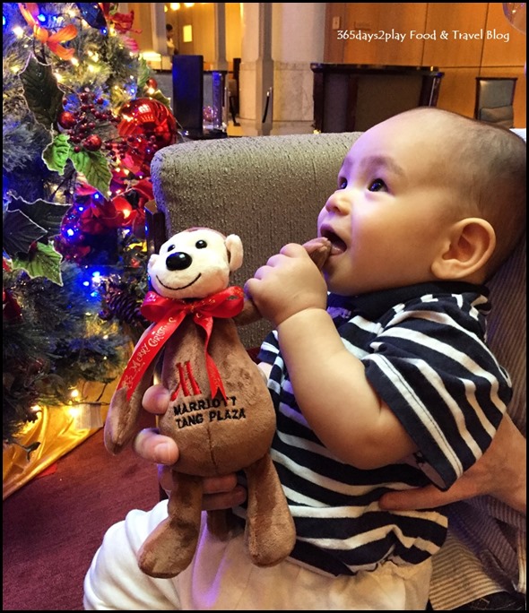 Baby holding soft toy looking at Christmas decorations